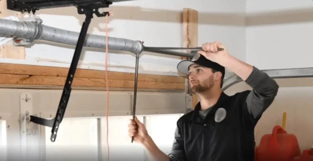 Garage door technician performing garage door maintenance Odessa TX inspecting internal motor components and gears of a ceiling mounted garage door opener.