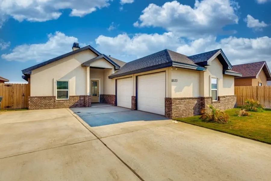 Two standard white single-car garage doors installed on a classic stucco and brick home under a clear blue sky, showing a completed residential project.