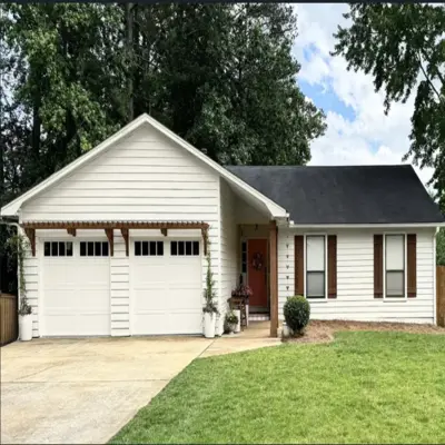 Two clean white long-panel residential garage doors featuring top windows underneath a custom decorative wood trellis pergola