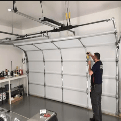 Local technician examining the high tension spring counter balance system during an emergency garage door repair Odessa TX residential house call.
