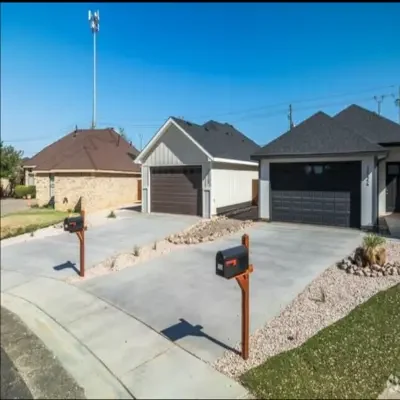 Row of modern residential homes with dark multi-panel garage doors, concrete driveways, and desert landscaping under a clear blue sky in a West Texas neighborhood serviced for garage door repairs.